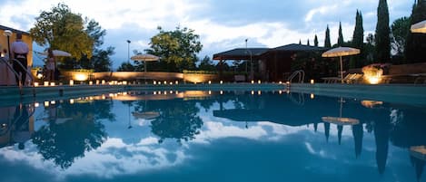 Una piscina al aire libre de temporada, sombrillas