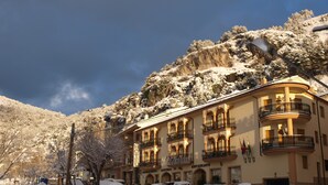 A hotel with multiple balconies, a restaurant, and a view of a snow-covered mountain.