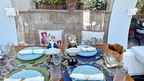 A table set with blue and green placemats, clear glassware, and gold cutlery.