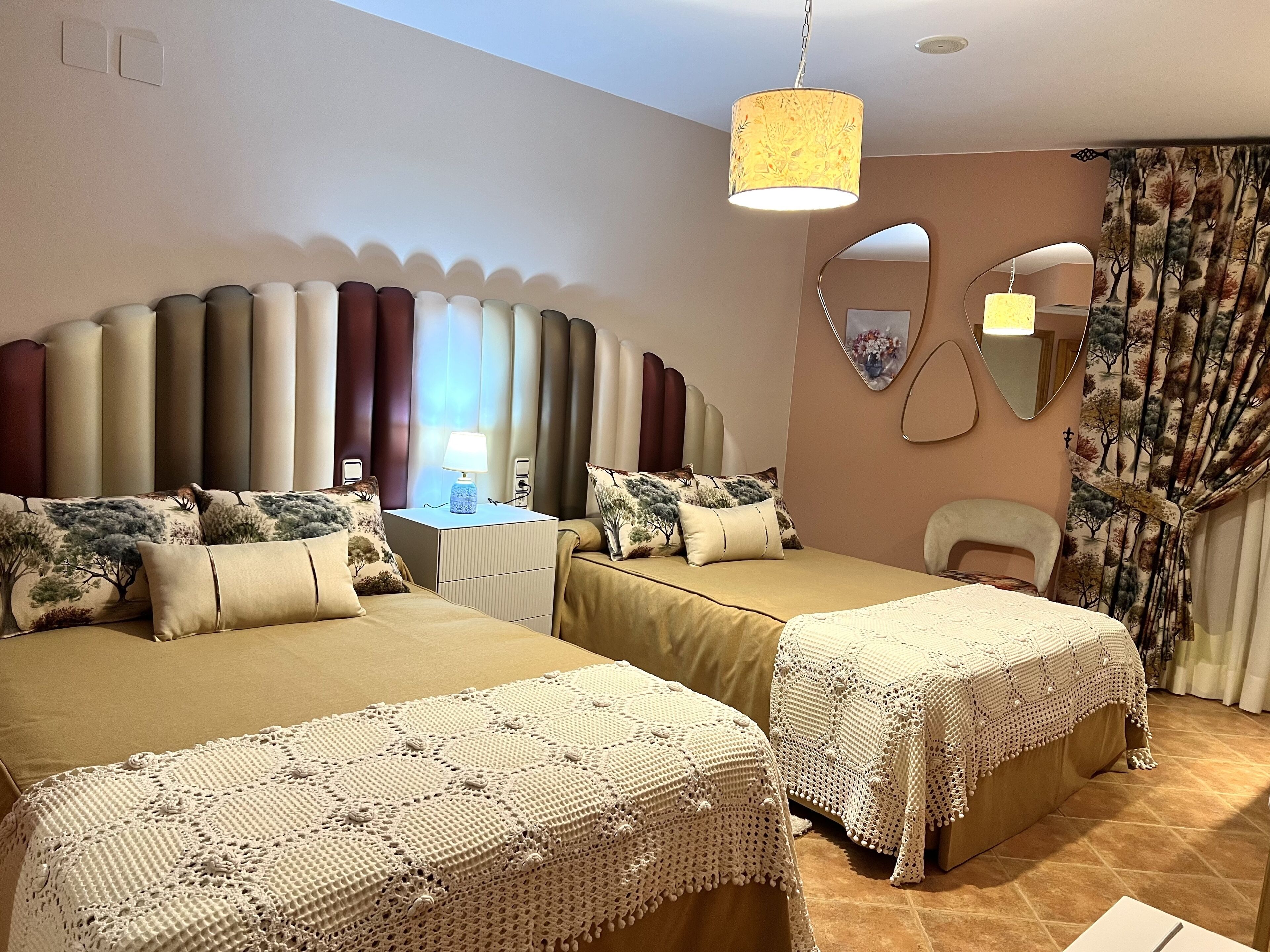 Habitación de hotel con dos camas, un espejo grande y una lámpara decorativa.