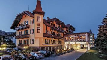 A hotel with multiple balconies, a prominent tower, and a well-lit entrance.