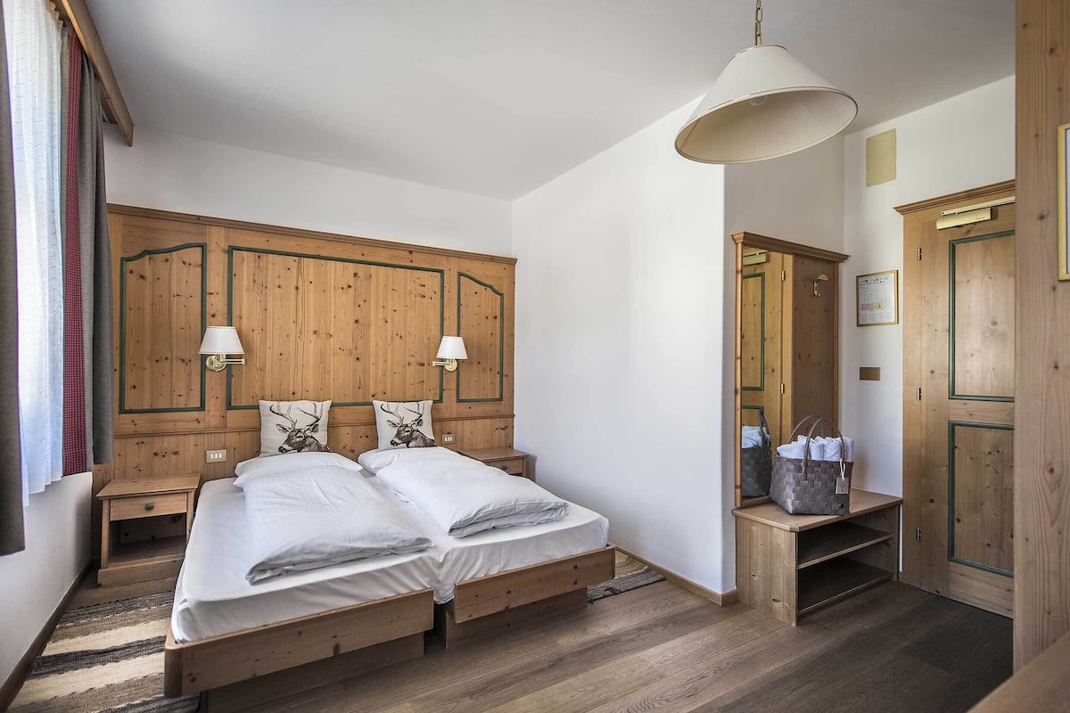 A bedroom with a wooden bed, nightstands, a lamp, and a wooden wardrobe.