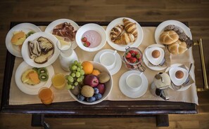 A breakfast tray with various foods and drinks, including pastries, fruits, and a glass of orange juice. - Hotel Cristallo (Dobbiaco)