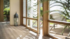 A wooden floor, a window with a metal grill, and a chair outside. - Hotel Cristallo (Dobbiaco)