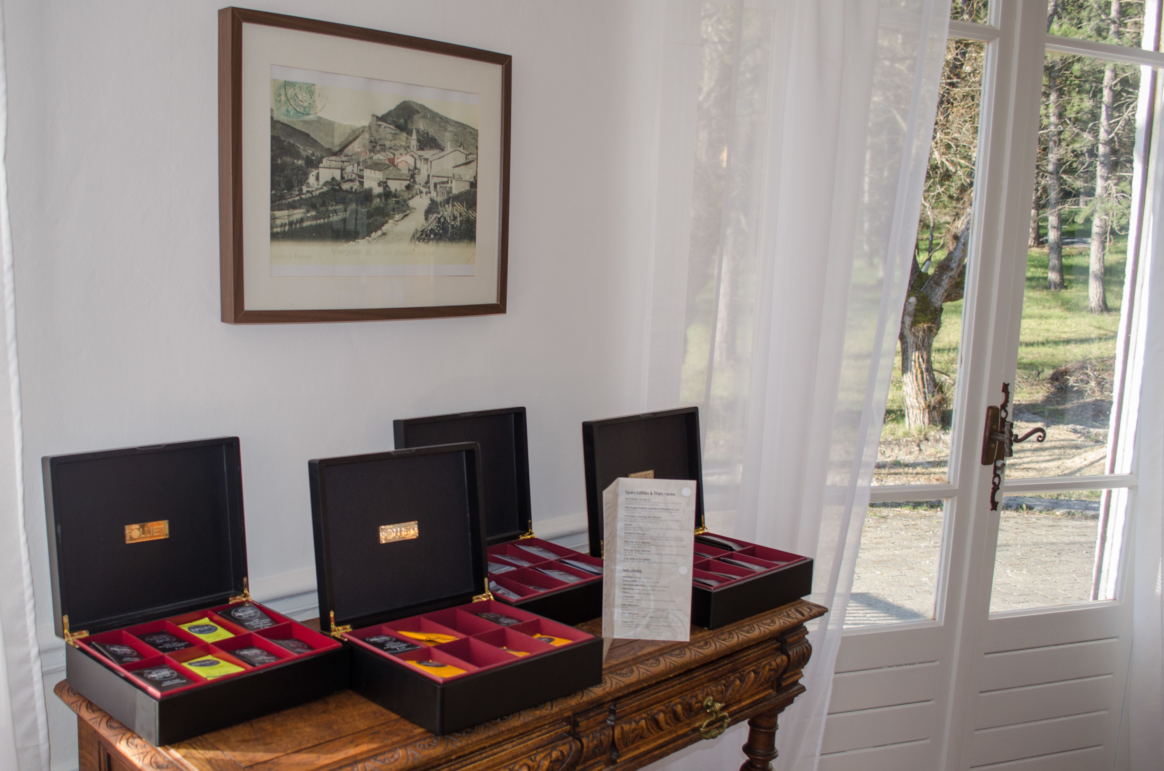 Three open jewelry boxes on a wooden table with a framed picture above.