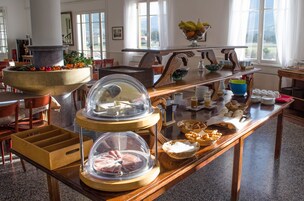 Disposição de buffet com diversos alimentos e um grande vaso de pedra com plantas.