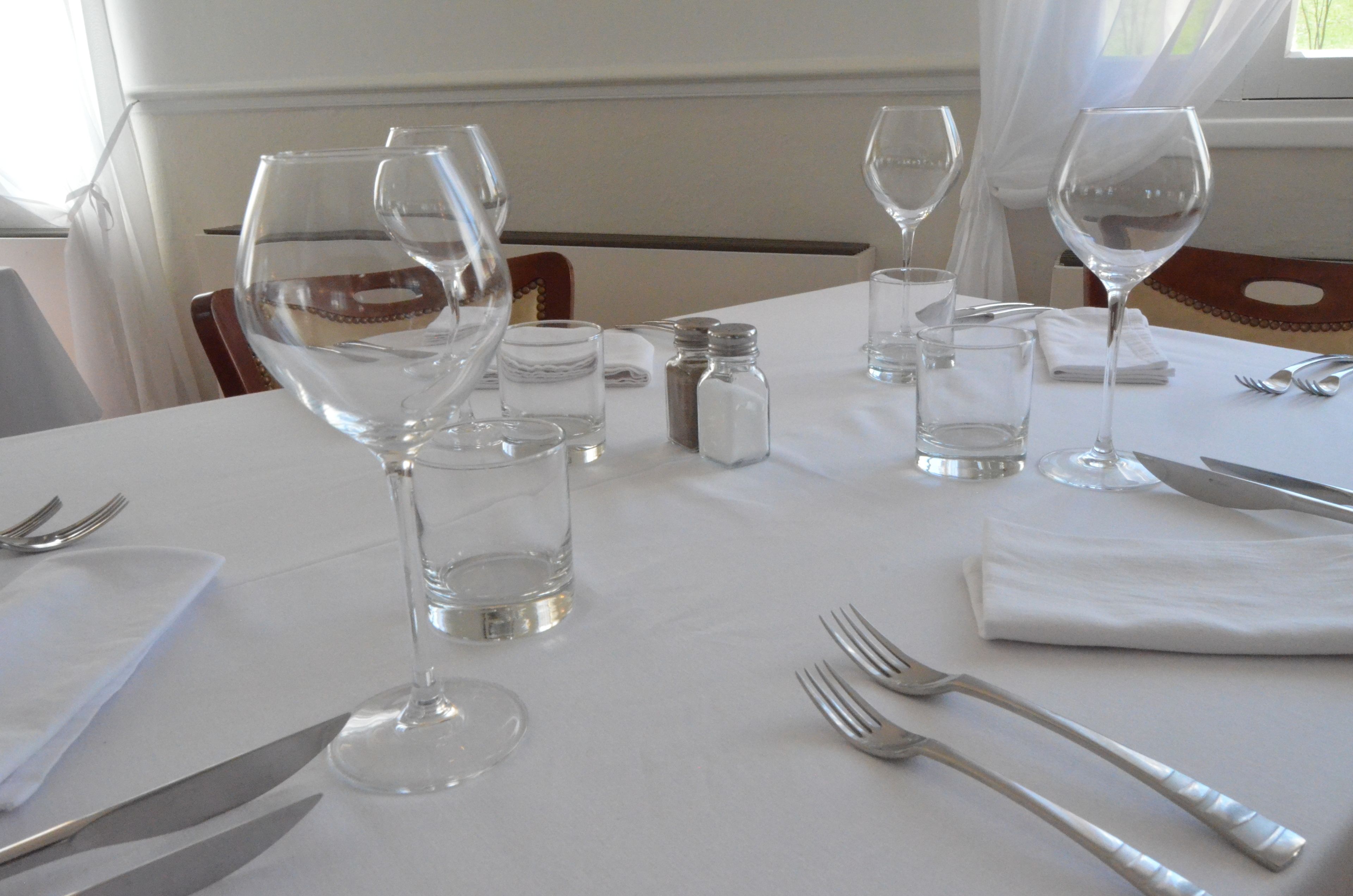 A table set for dining with wine glasses, water glasses, and cutlery.