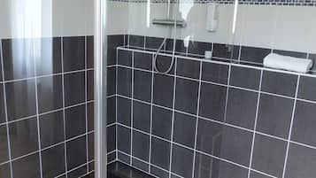 Ein modernes Duschbad mit Glastür, gefliesten Wänden und einer Metallbank.