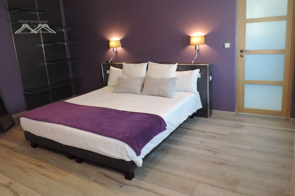Een slaapkamer met een bed, twee bedlampen, een kledingkast en een deur.