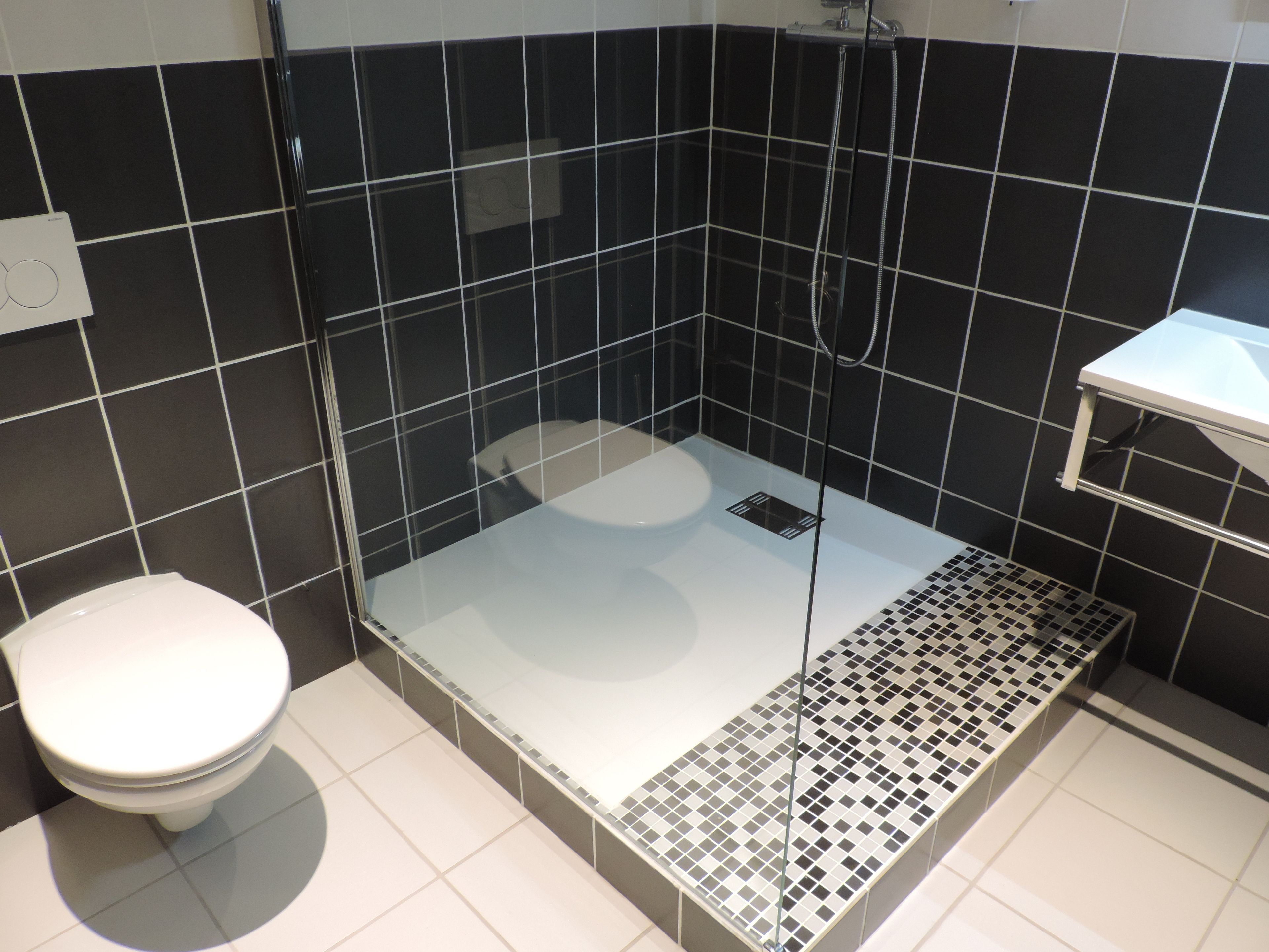 Un baño con ducha de vidrio, inodoro blanco y piso de baldosas.