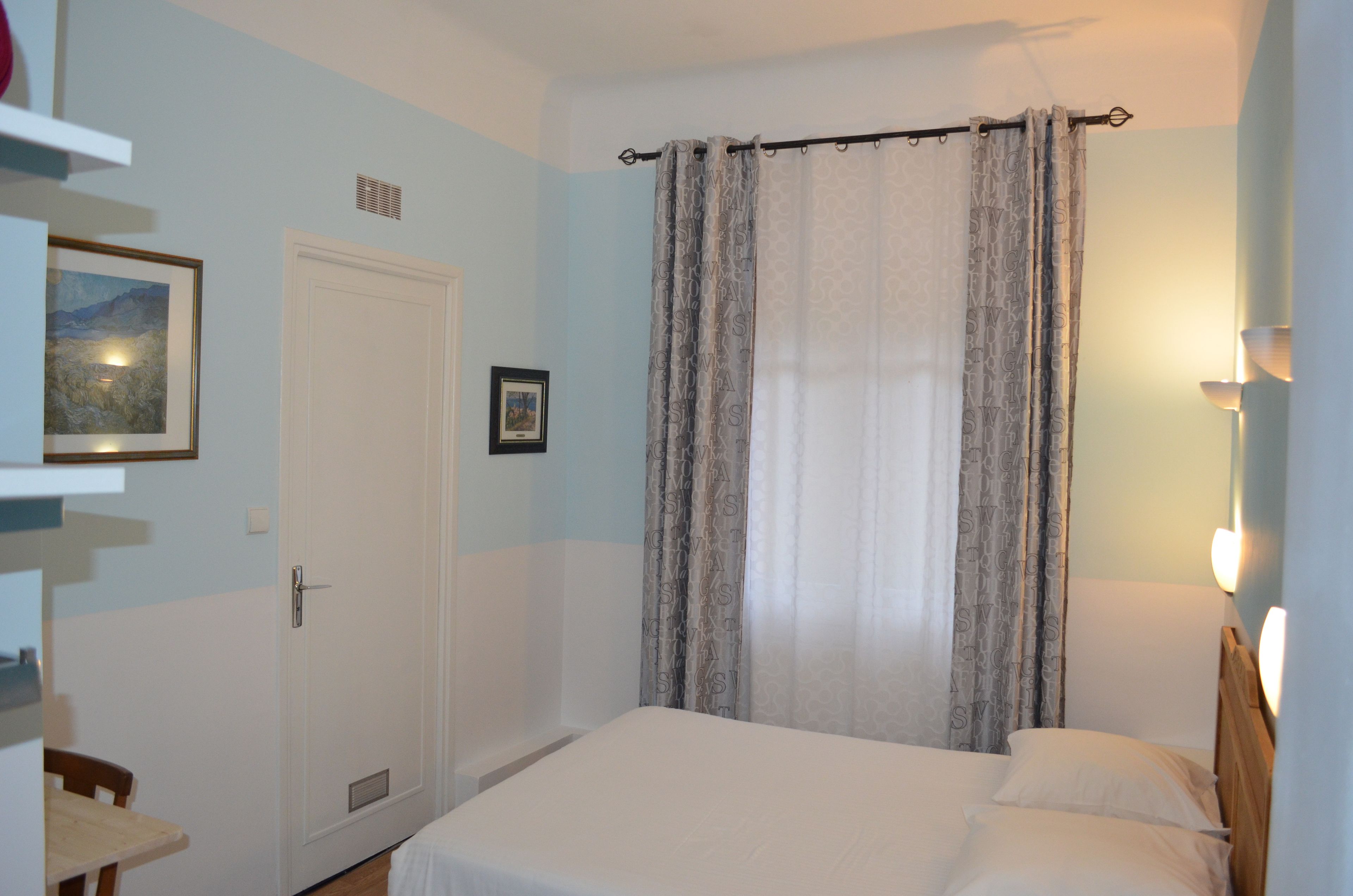 Une chambre à coucher avec un lit, une porte, une chaise et une étagère fixée au mur.