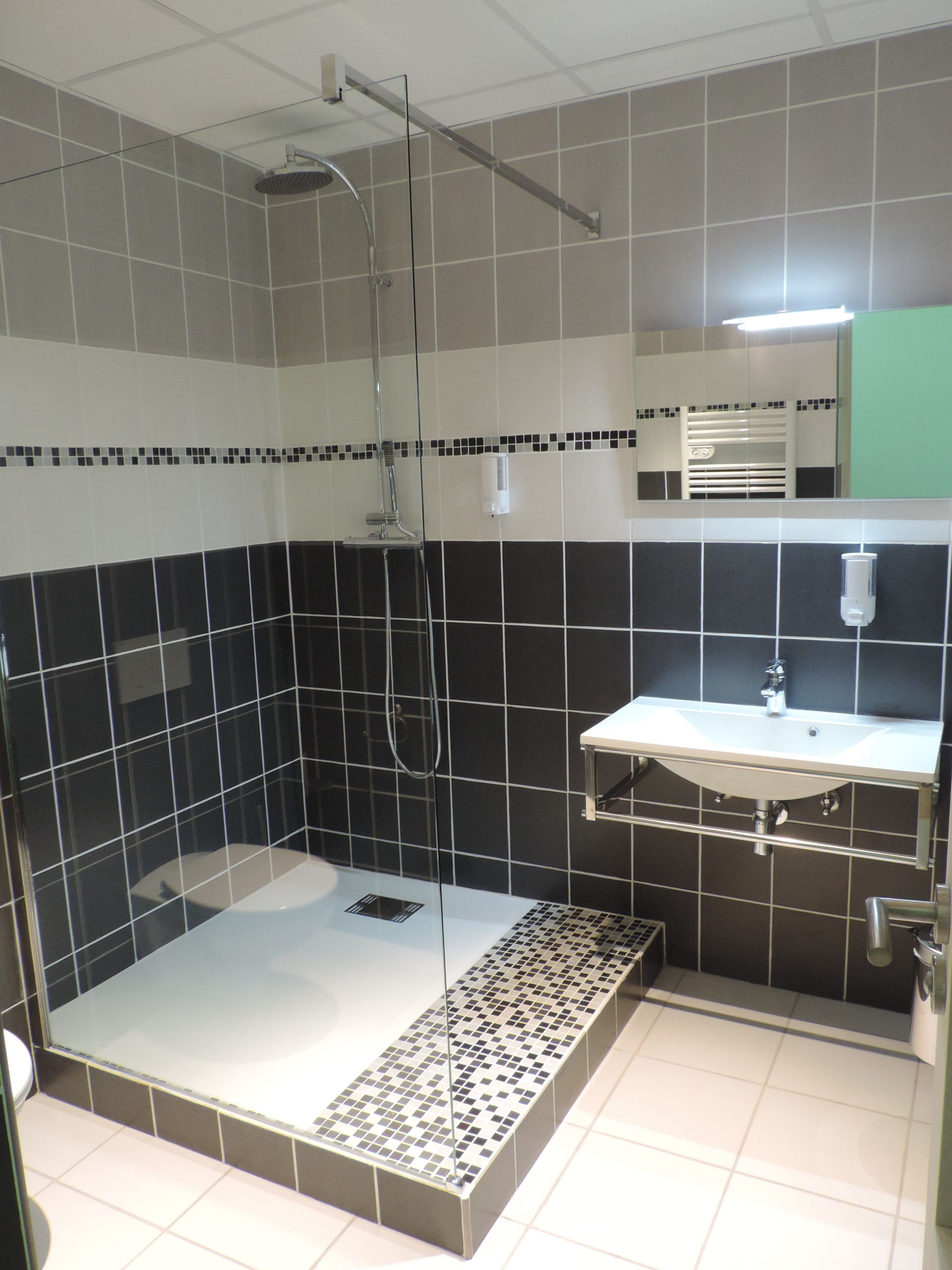 A modern bathroom with a glass-enclosed shower, a white sink, and a tiled floor.