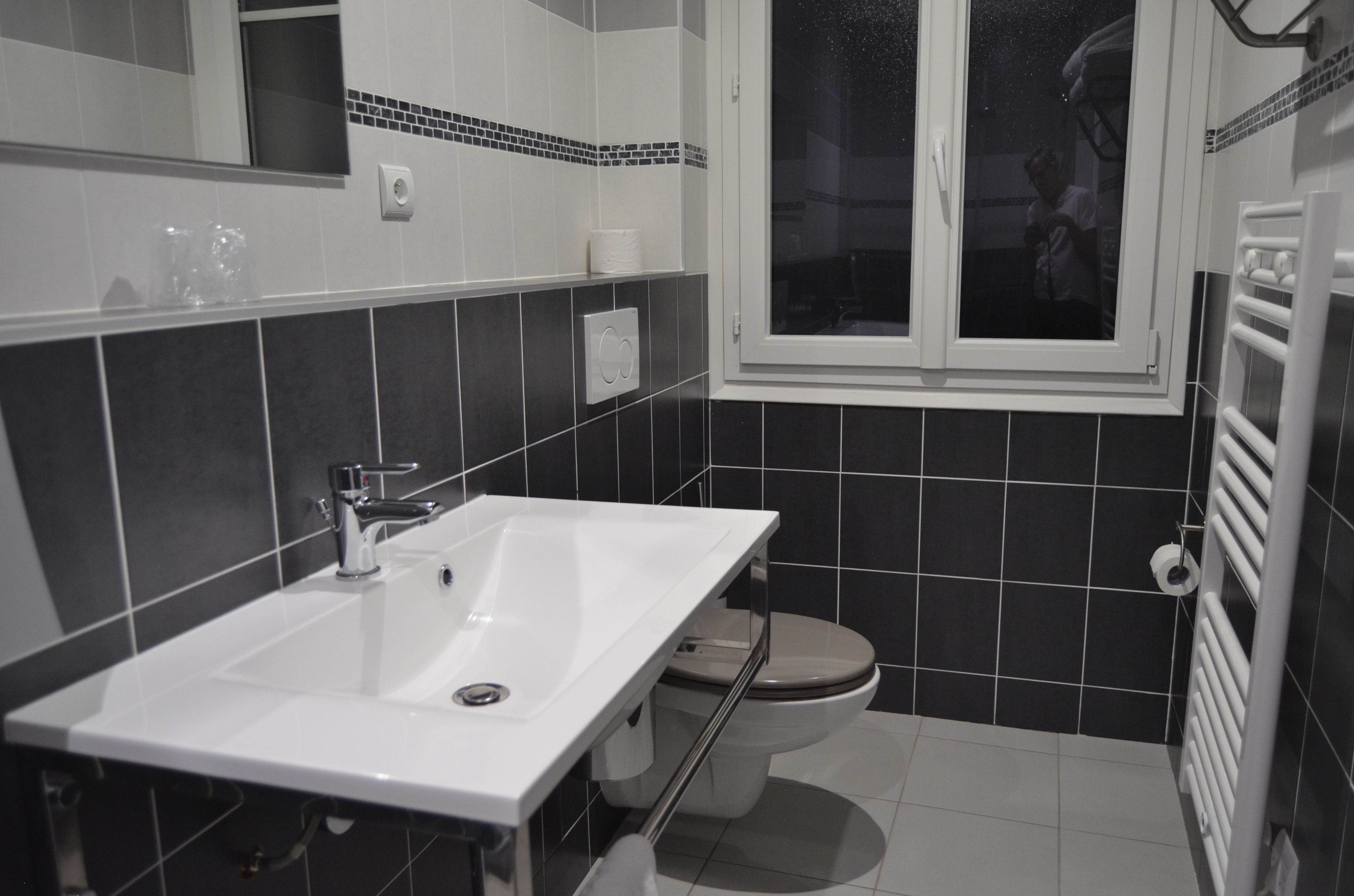 A bathroom with a white sink, a toilet, and a window.
