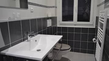 A bathroom with a white sink, a toilet, and a window.