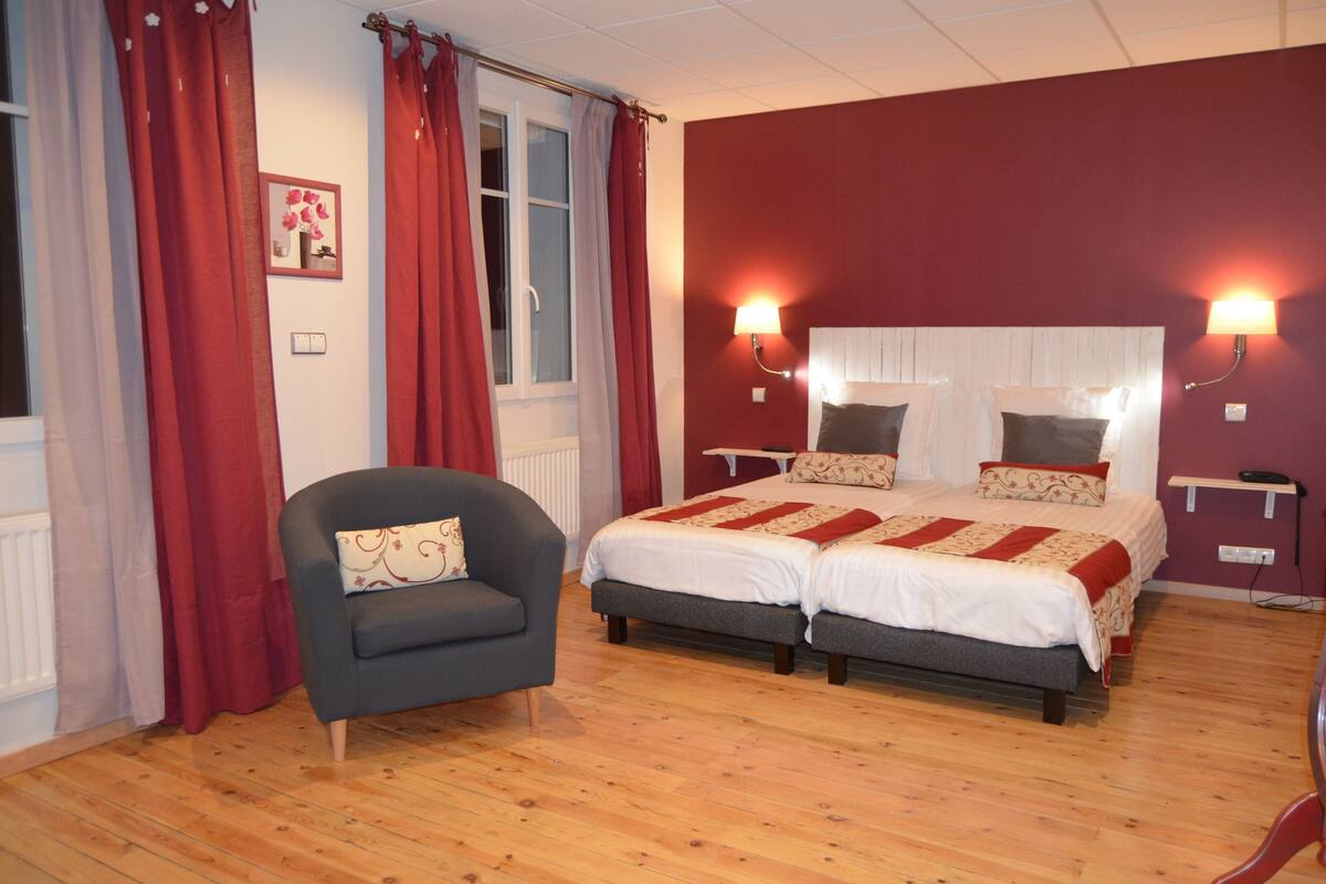 Een slaapkamer met twee bedden, een stoel en twee bedlampjes.