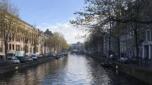 A canal lined with historic buildings, parked cars, and bicycles. - Amsterdam4holiday (Amsterdam)