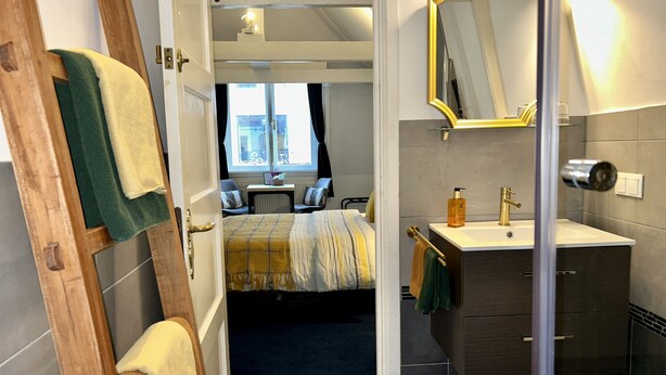 A modern hotel room with a bed, a bathroom with a mirror, and a view of the city through the window. - Amsterdam4holiday (Amsterdam)