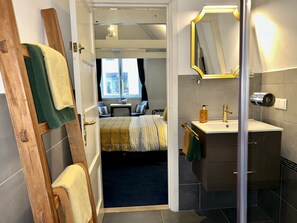 Una habitación de hotel moderna con una cama, un baño con espejo y vistas a la ciudad por la ventana.