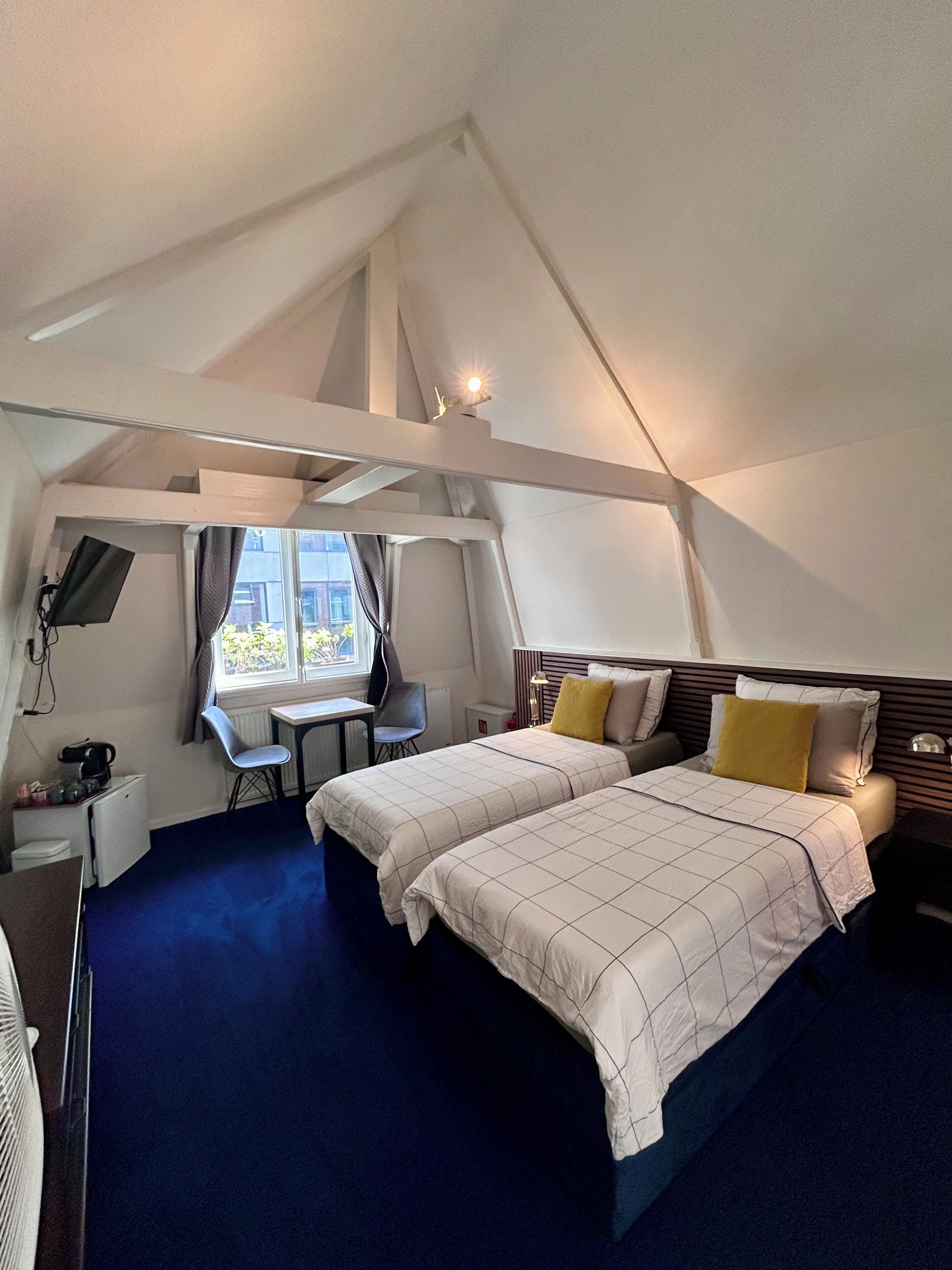 A bedroom with two beds, a desk, and a chair.