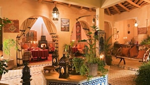 A cozy interior with a fireplace, wooden furniture, and potted plants.