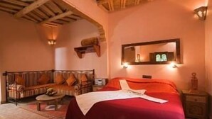 A room with a bed, a sofa, a small table, and a mirror.