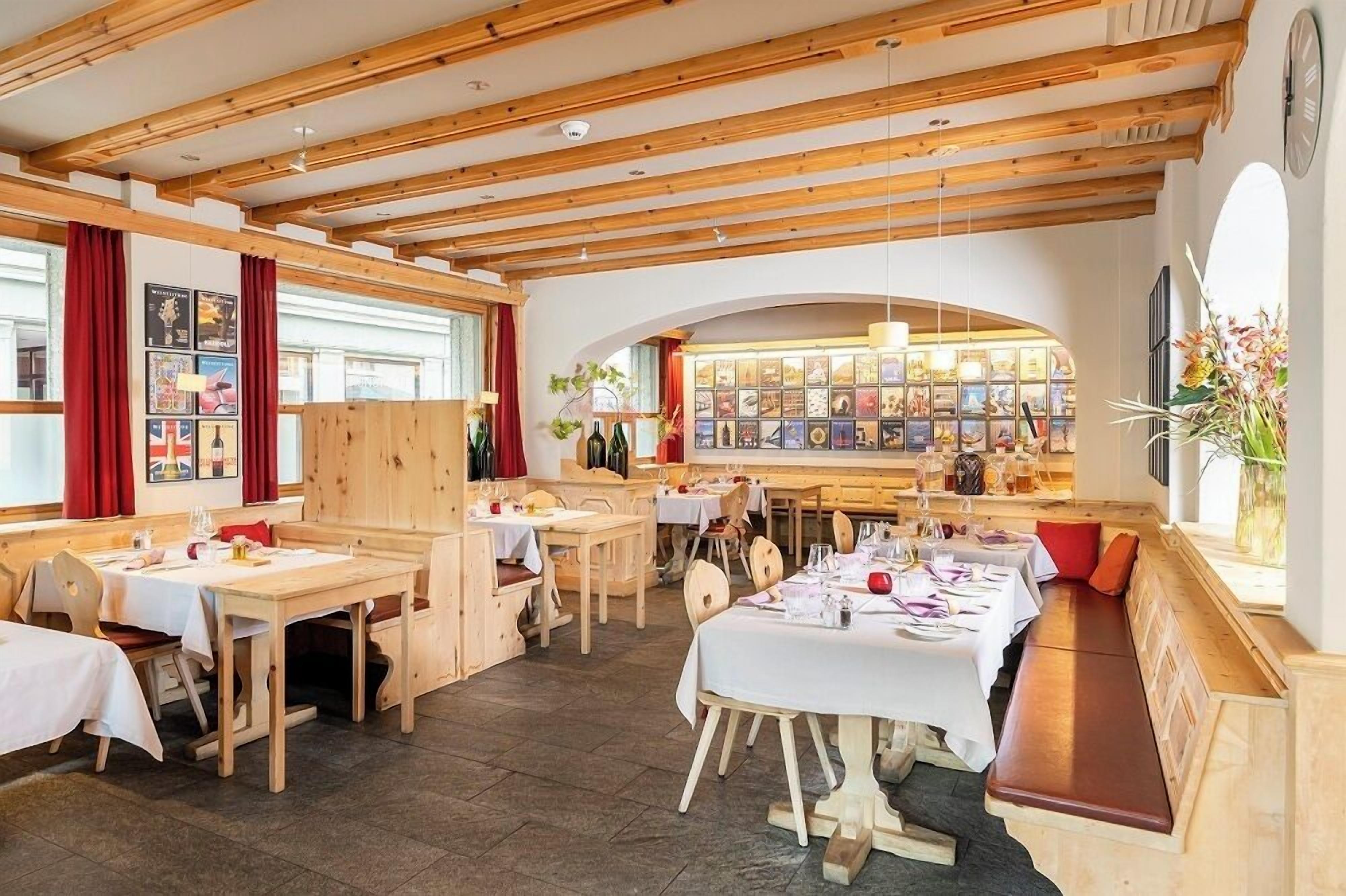 Un restaurant avec des poutres en bois, des tables dressées pour le repas et un présentoir à vin.