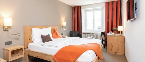 Une chambre d’hôtel avec un lit en bois, des tables de chevet, un bureau et une chaise.