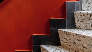 Eine Treppe mit schwarz-weißen, gefleckten Stufen und einer roten Wand.