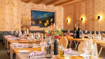 A restaurant with wooden tables set for dining, featuring clear glassware and floral centerpieces.