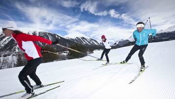 Tres personas esquiando de fondo en una pendiente nevada, con montañas al fondo.