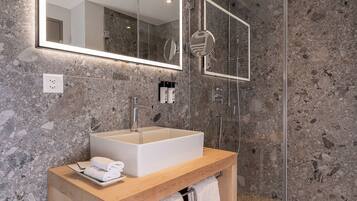 Une salle de bain moderne avec un grand miroir, un lavabo rectangulaire et une douche à parois de verre.