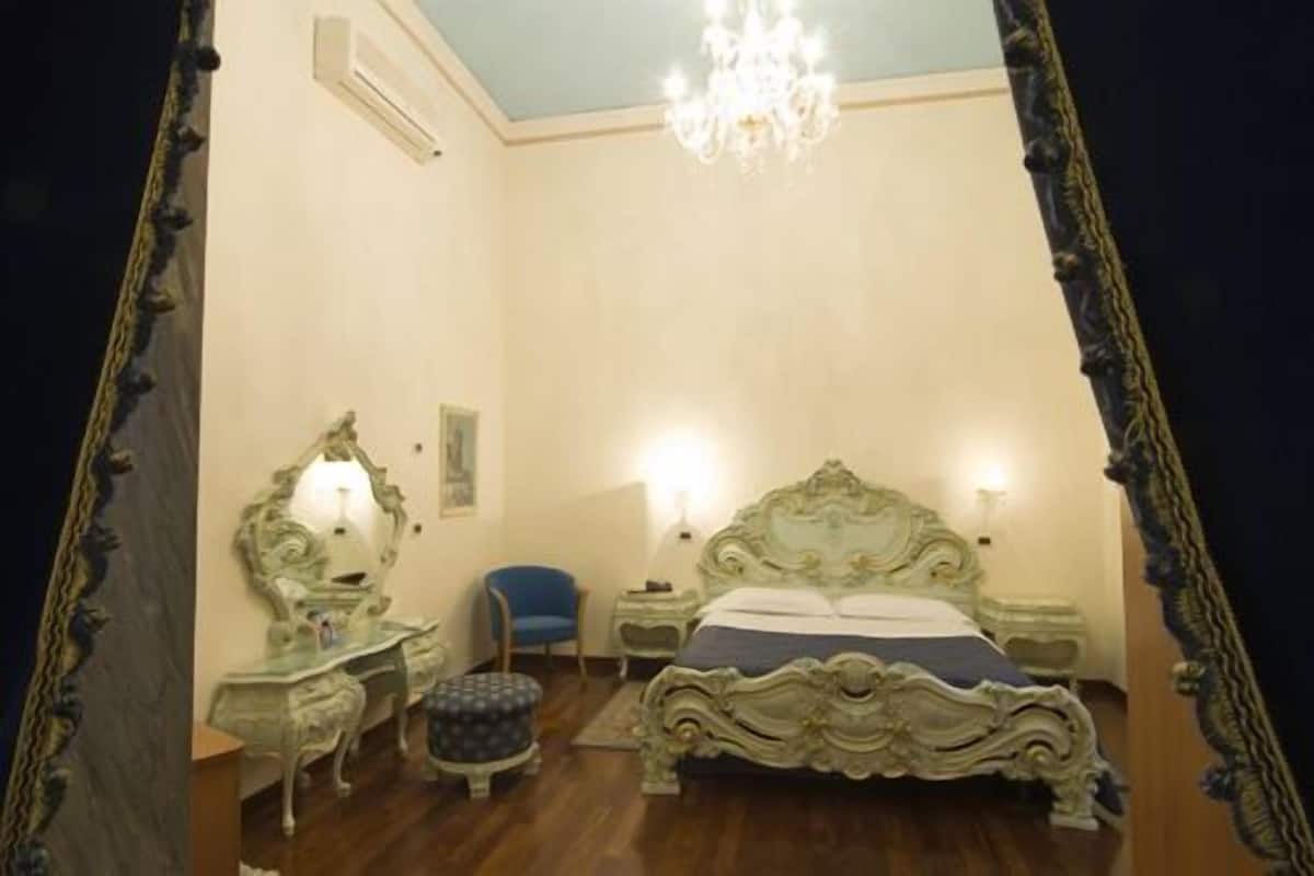 A bedroom with a large bed, a dresser, a chair, and a chandelier.