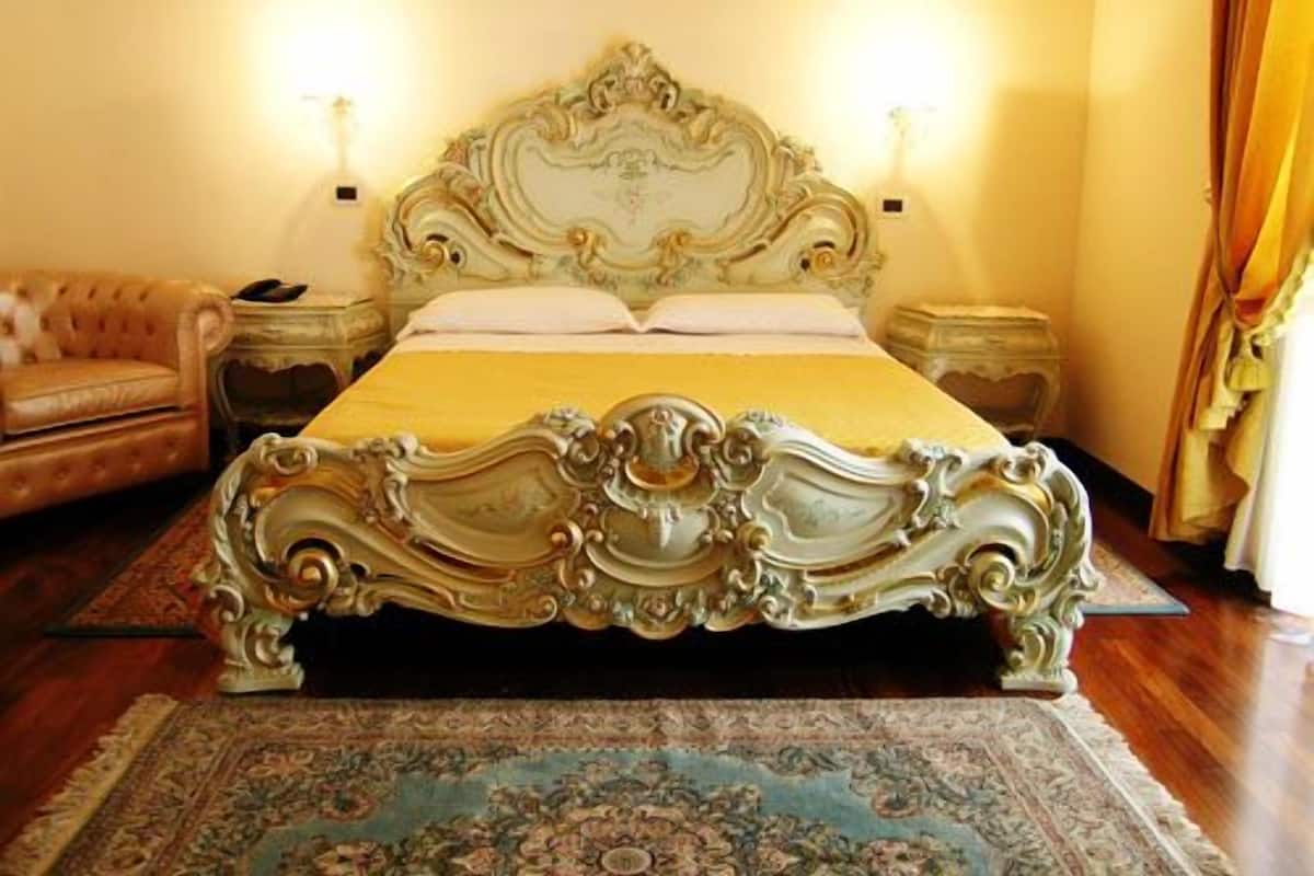 A bed with ornate carvings, a matching headboard, and a floral-patterned rug.