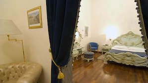 Una habitación con una cama grande, una silla, una mesita y una lámpara.