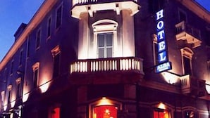 Un hotel con un llamativo letrero que dice 'HOTEL', un balcón con barandillas y una puerta de entrada grande.