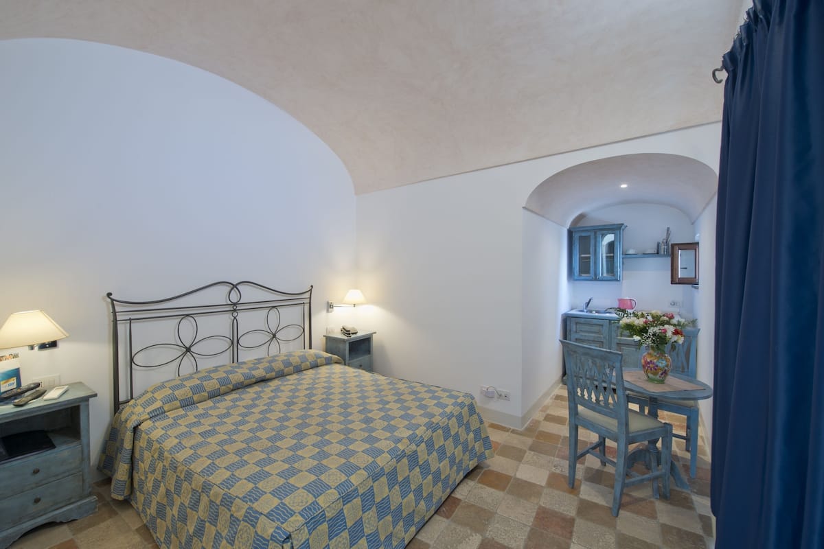 Un dormitorio con cama, mesitas de noche, un escritorio y una silla.