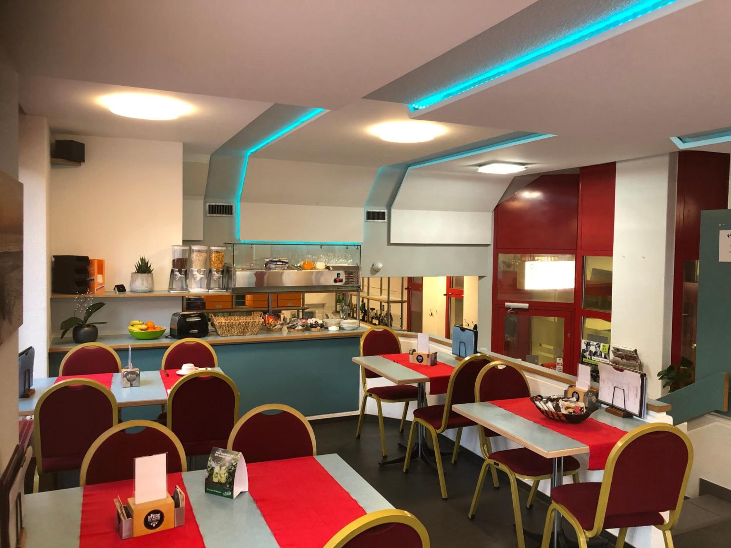 Un restaurante con mesas y sillas, una barra con productos alimenticios y una zona de cocina.