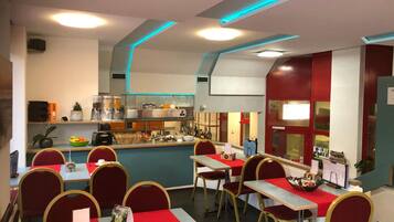 Un restaurante con mesas y sillas, una barra con productos alimenticios y una zona de cocina.