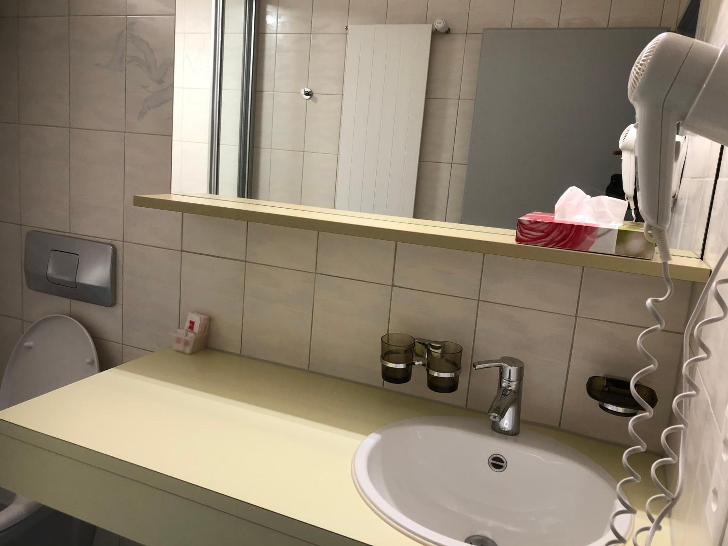 Ein Badezimmer mit Waschbecken, Spiegel und Haartrockner auf einem Regal.