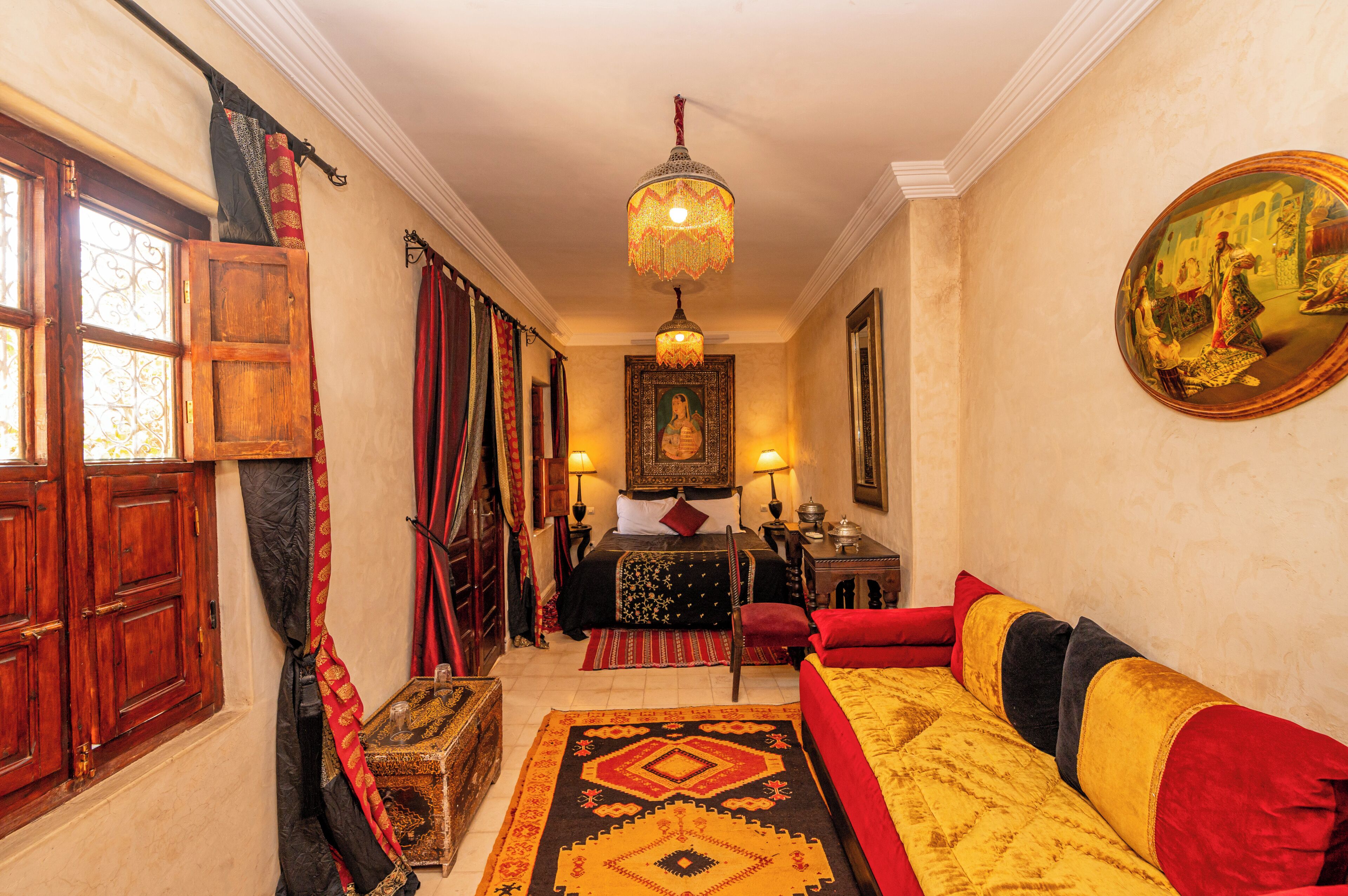 Une chambre traditionnelle avec un lit, un canapé, un lustre et un tableau au mur.