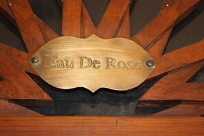A wooden sign with the inscription "Eau De Rose" mounted on a dark background.