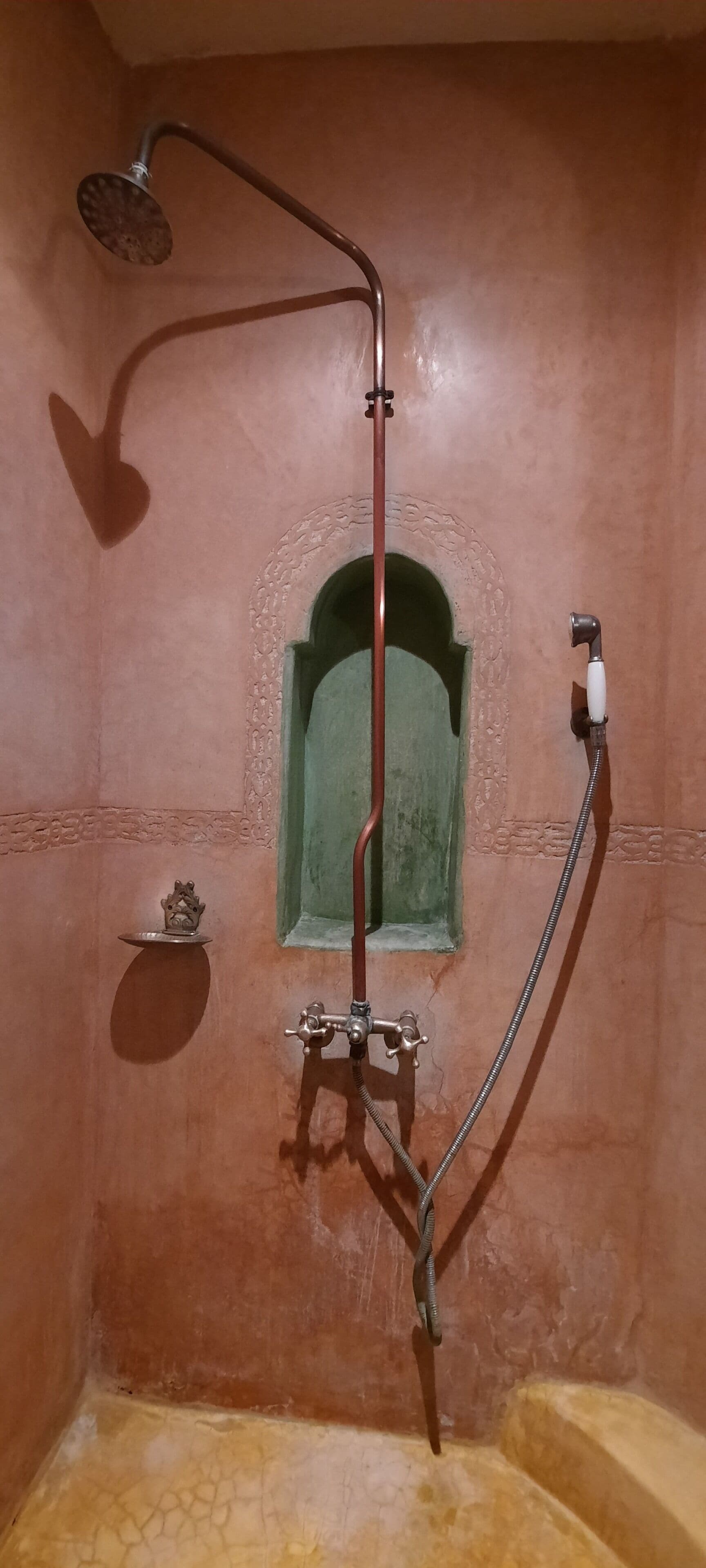 A bathroom with a shower, a small window, and a decorative plate on the wall.