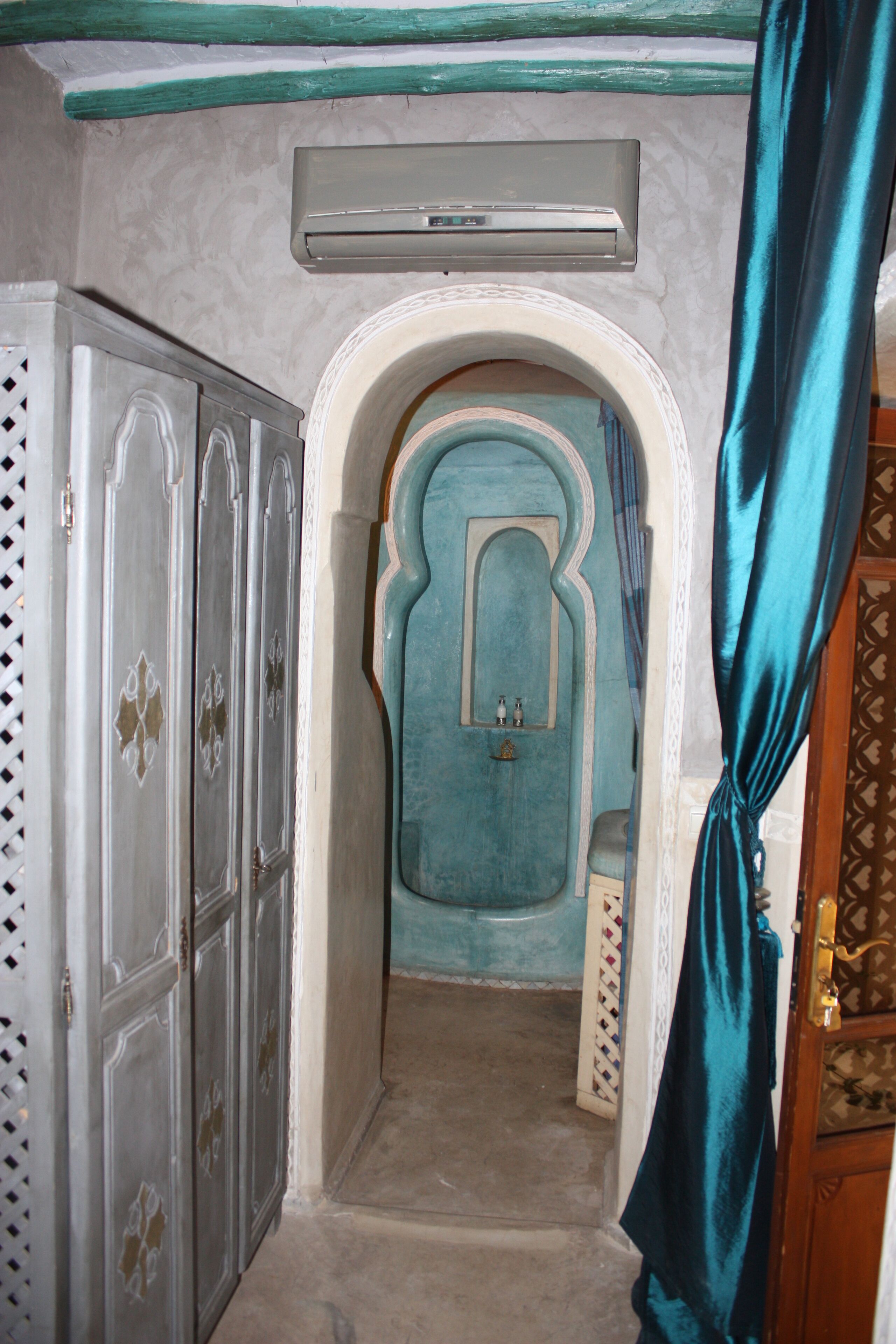 Un corridoio con una porta blu, un condizionatore d'aria bianco e una tenda blu.