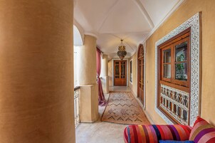 Un pasillo con alfombras estampadas, puertas de madera ornamentadas y un farol colgante.