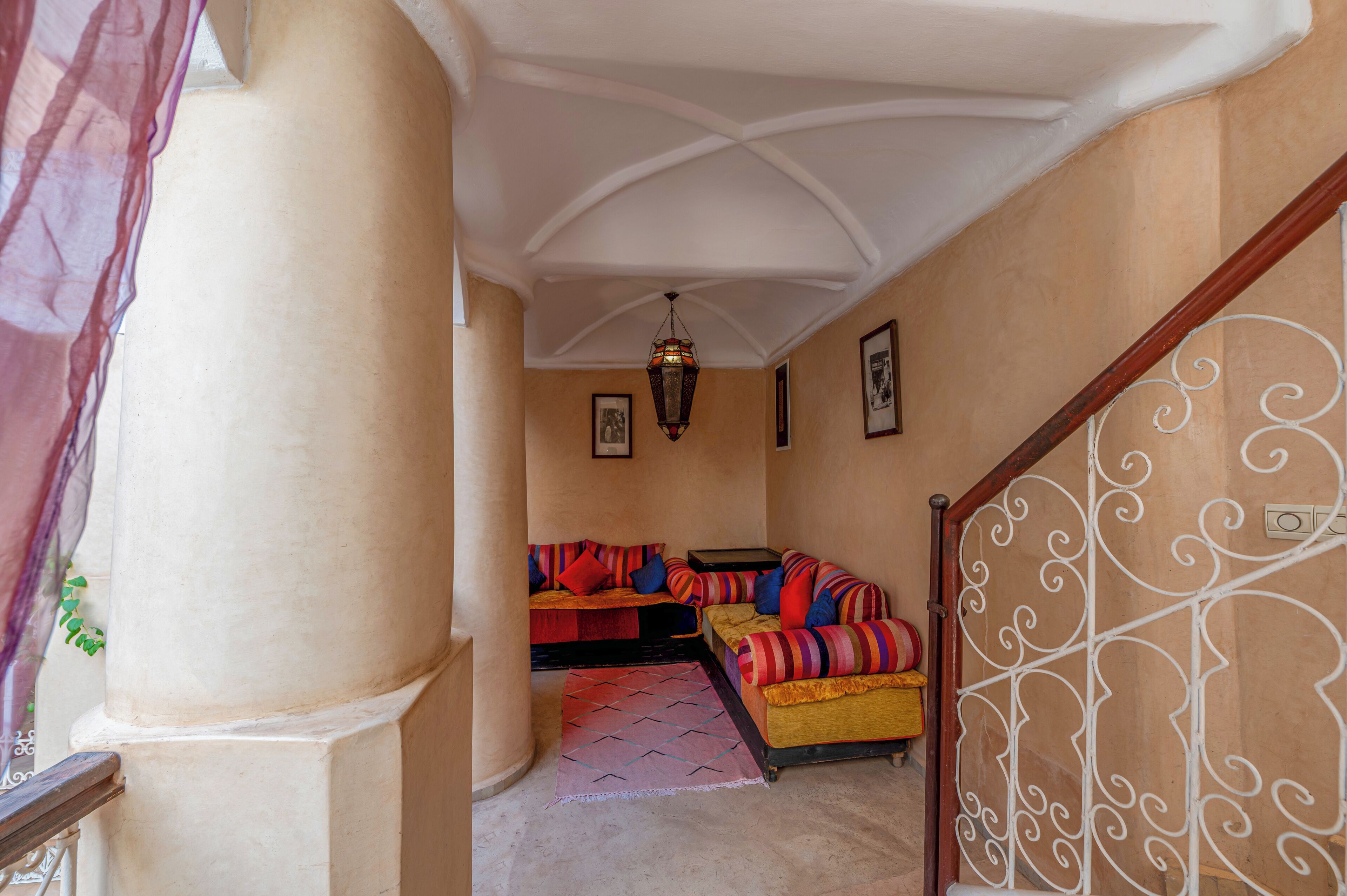 Un couloir avec un escalier menant à une pièce où se trouvent un canapé et un lit.