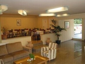 A spacious lobby with a seating area, a staircase, and a large potted plant. - Phaistos Hotel (Nafplio)