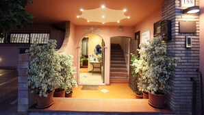 La entrada del Hotel Mendolía Beach, con una escalera que conduce al interior, plantas en macetas y un cartel con el nombre del hotel.