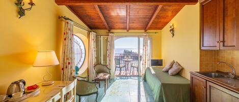 A compact kitchen with a dining area, a view through a window, and a wooden ceiling.