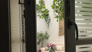 Une porte ouverte donne sur une pièce dont le sol est décoré de motifs, où se trouvent un canap é et un vase rempli de fleurs.