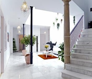 A spacious hallway with a marble floor, a staircase, and a chandelier. - Hotel Un Patio al Sur (Seville)
